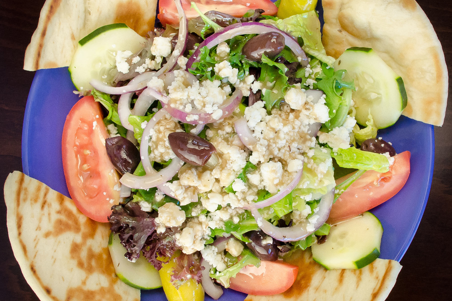 a blue plate topped with a salad and pita bread.