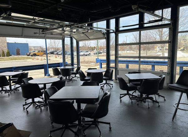 a room with tables and chairs and a view of a parking lot.
