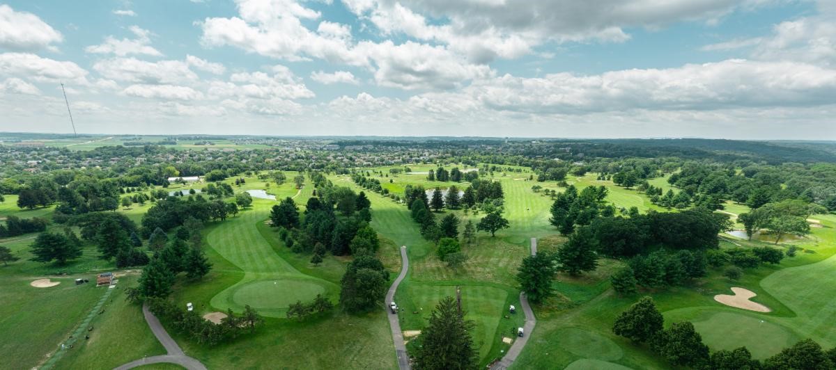 an aerial view of a golf course surrounded by trees.