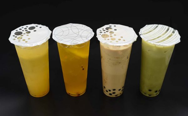 Four cups of bubble tea are lined up on a black surface.