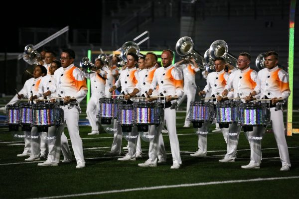 a group of men in white and orange uniforms playing instruments.