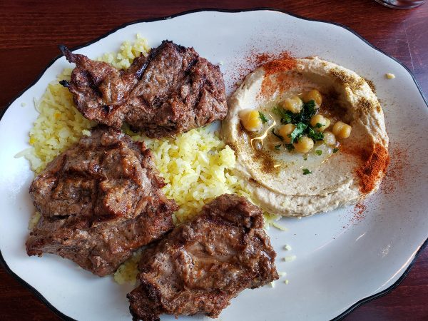 A plate of food with meat, rice and hummus.