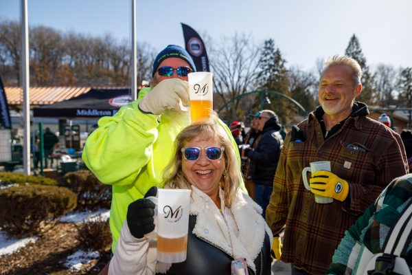 At the Capital Brewery & Bier Garten's winter festival, people gathered in cozy winter clothing, holding mugs of beer under the clear, sunny sky. They shared laughter and smiles, embodying the festive spirit of Bockfest.