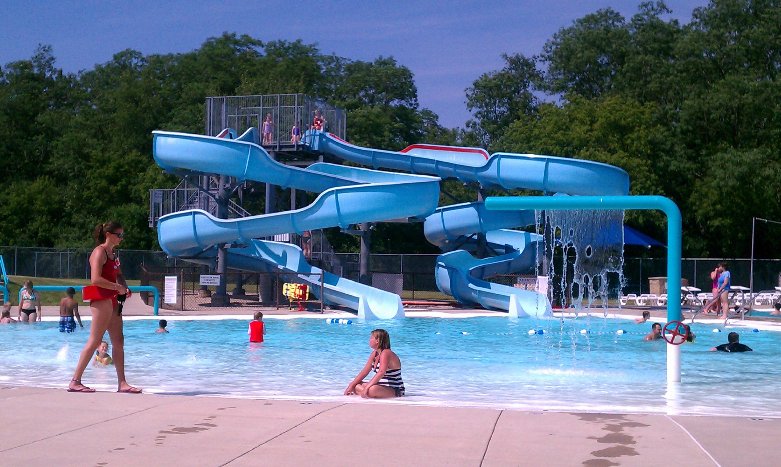 a group of people playing in a pool with a water slide.