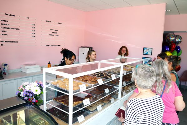 a group of people standing around a bakery counter.