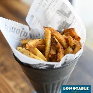 a bowl of french fries sitting on top of a newspaper.