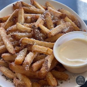 a plate of french fries with dipping sauce.
