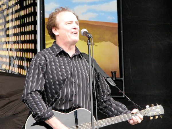 a man holding a guitar and singing into a microphone.