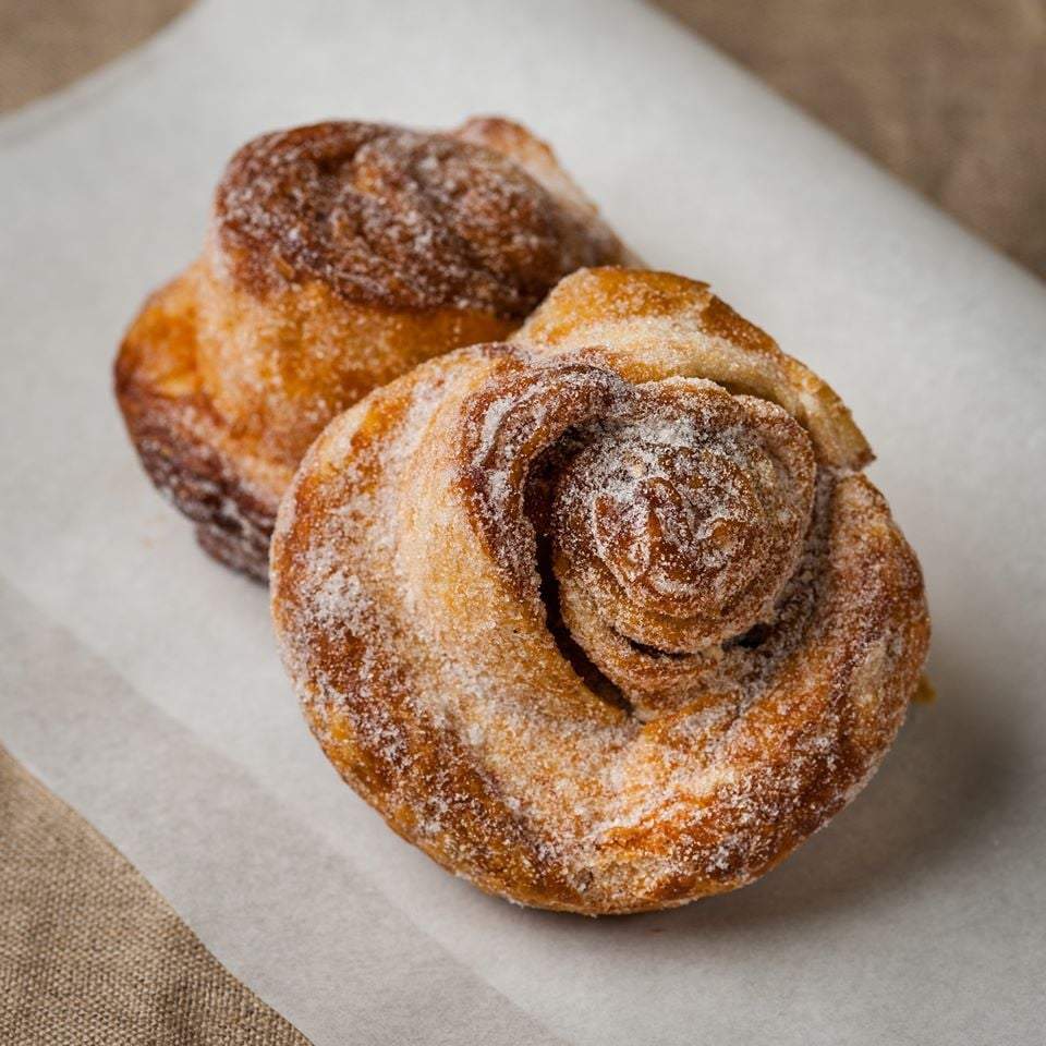 Two cinnamon buns are sitting on a piece of paper.