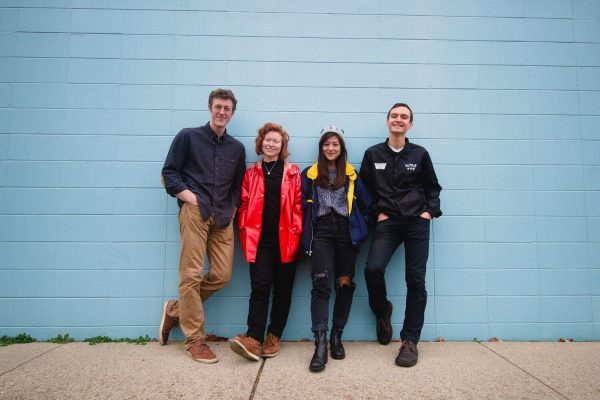 Four people standing in front of a blue wall.