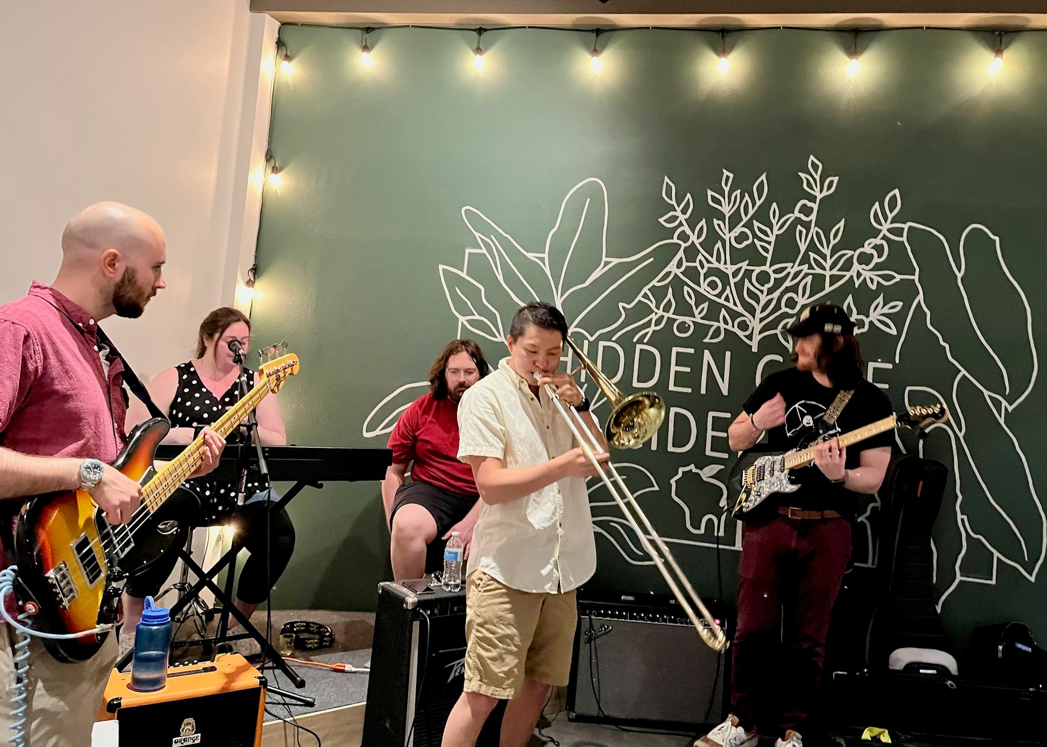A group of people playing music in front of a chalkboard.