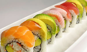 A sushi roll is arranged on a white plate.