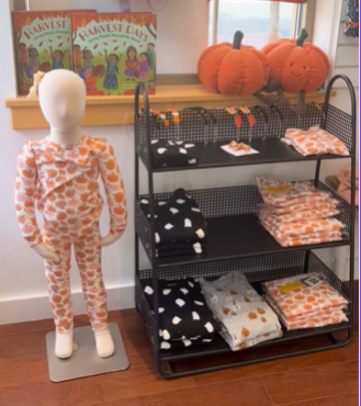 A mannequin with pumpkins and pajamas on a shelf.