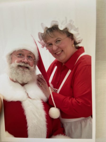 Santa claus and his wife pose for a photo.