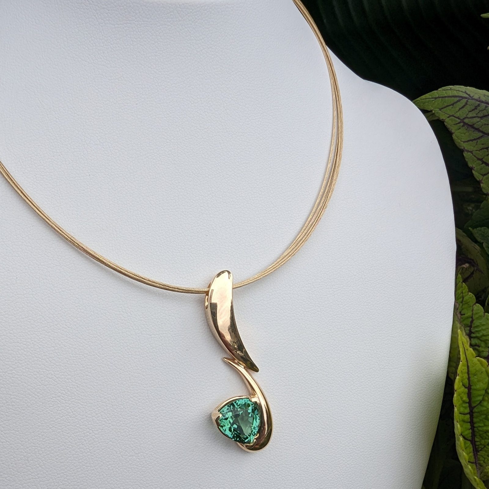 An emerald green pendant on a gold chain.