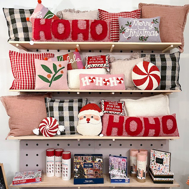 A display of christmas decorations and pillows on a shelf.