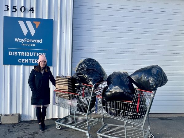 A woman standing in front of a warehouse with carts full of bags.