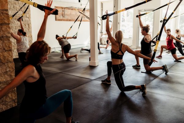 A group of people doing a trx workout in a gym.