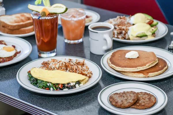 A table full of pancakes, eggs, and drinks.