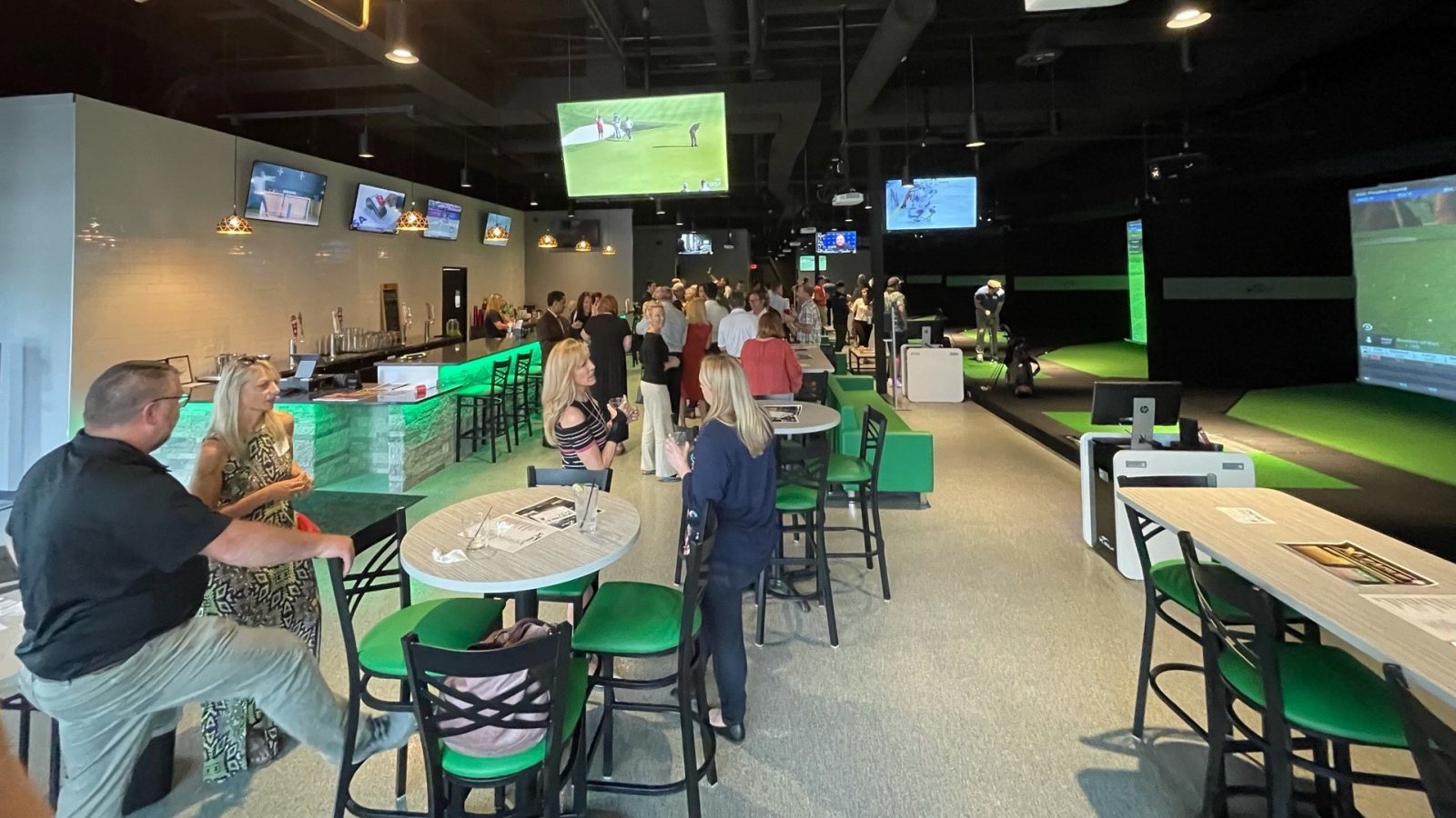 A group of people in a golf game room.