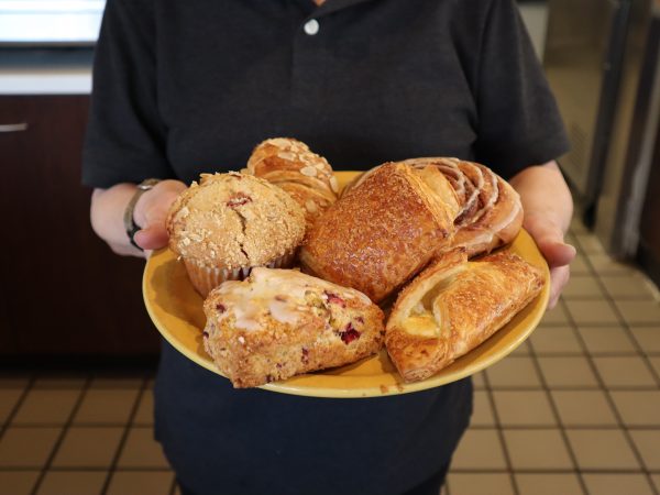 A woman holding a plate of pastries.