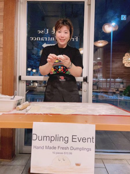 A woman standing in front of a table with a sign that says dumpling event.