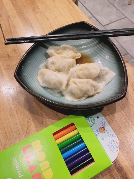 A bowl of dumplings with chopsticks and colored pencils.