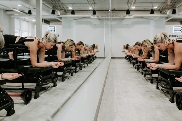 A group of women practicing pilates in a gym.