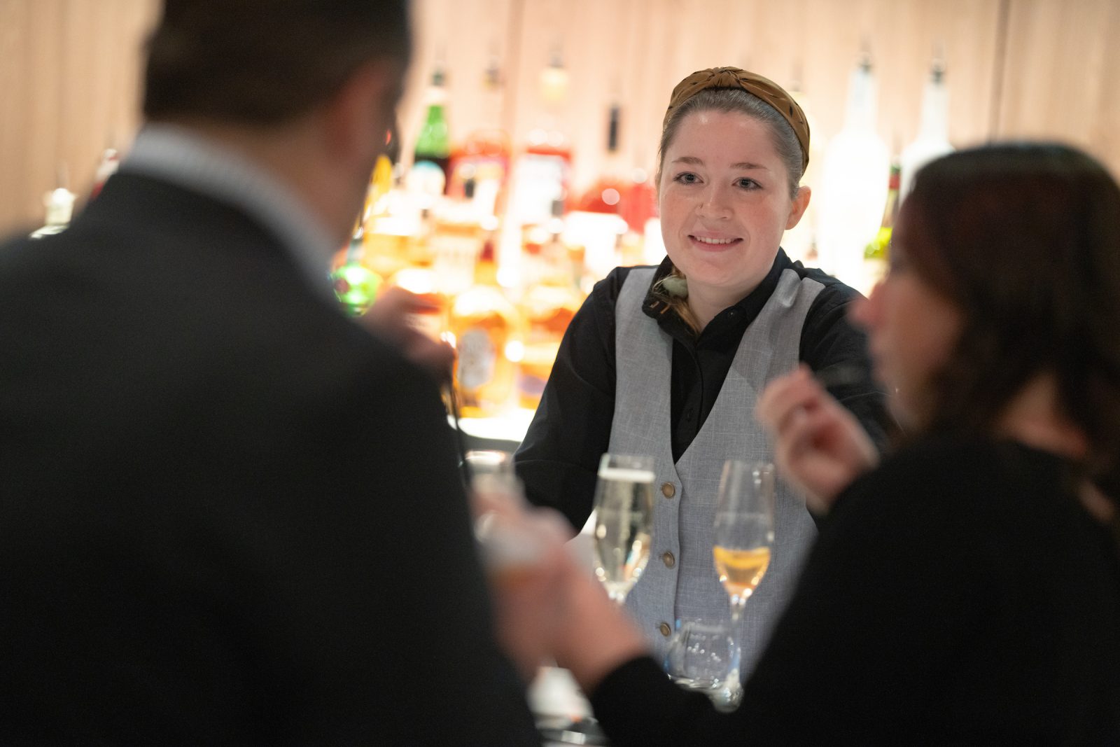 A bartender smiling at a group of people at a bar.