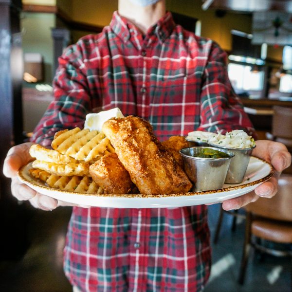 A man holding a plate of fish and chips.