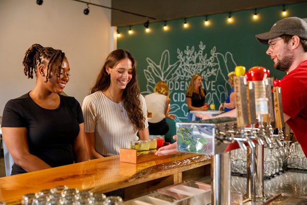 A group of people standing at a bar.