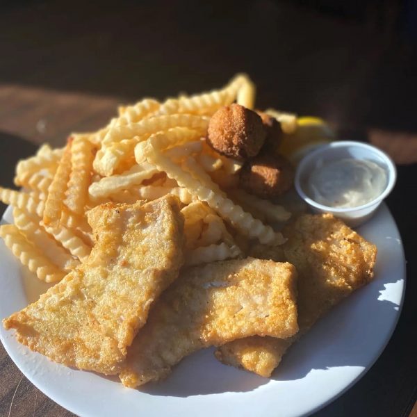 A plate of fish and chips with dipping sauce.
