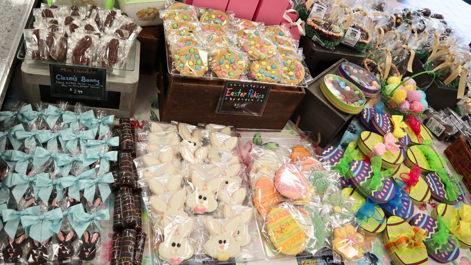 An assortment of colorful Easter treats, including cookies, bunnies, and eggs, from Middleton's finest bakeries is displayed on a market table.