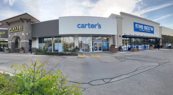 Storefronts featuring signage for Carter's, Five Below, and Playtri in a shopping plaza with a small green bush in the foreground.