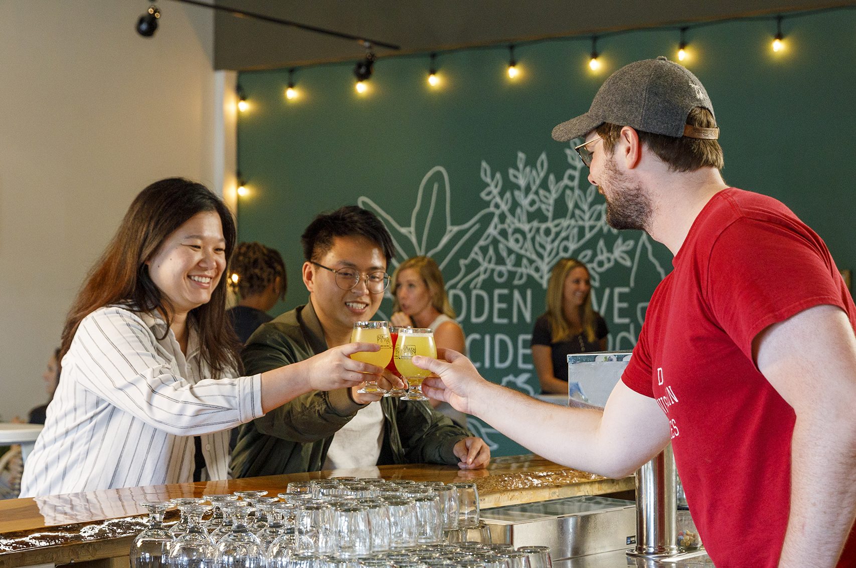 A group of people at a bar with a glass of beer.