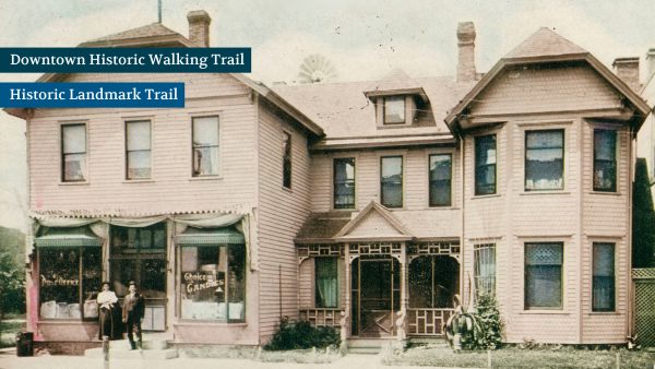 Historic two-story pink house with ornate woodwork. Two people stand outside near a sign reading "Choice Gardens." Text overlays read "Downtown Historic Walking Trail" and "Historic Landmark Trail.