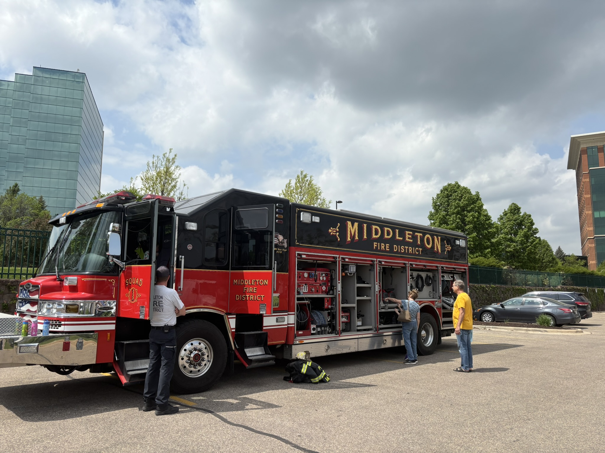 A Middleton Fire District fire truck is parked outdoors as three people stand nearby, one in uniform, with equipment compartments open.