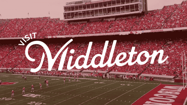 A crowded football stadium with “Visit Middleton” written in large script across the image; players are on the field and spectators fill the stands.