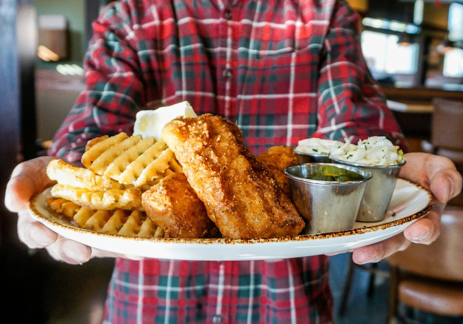 A man holding a plate of fish and chips.