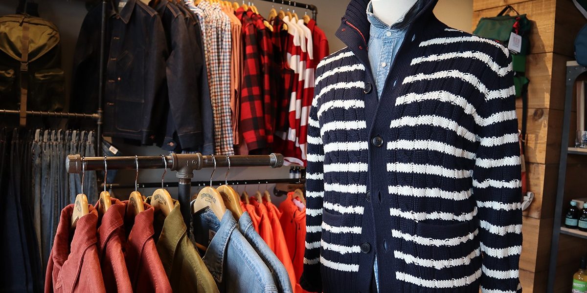a man's sweater and jacket are on display in a clothing store