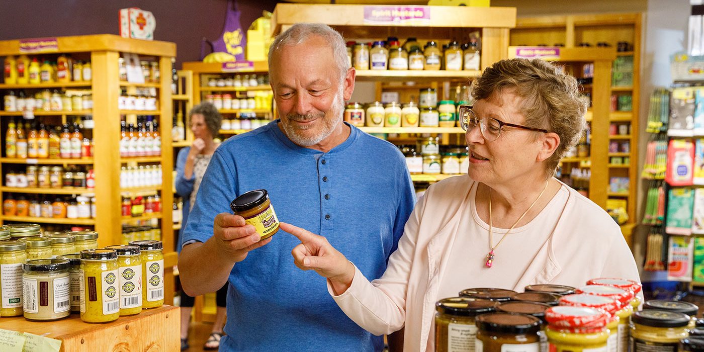 a man and woman looking at a jar of jam