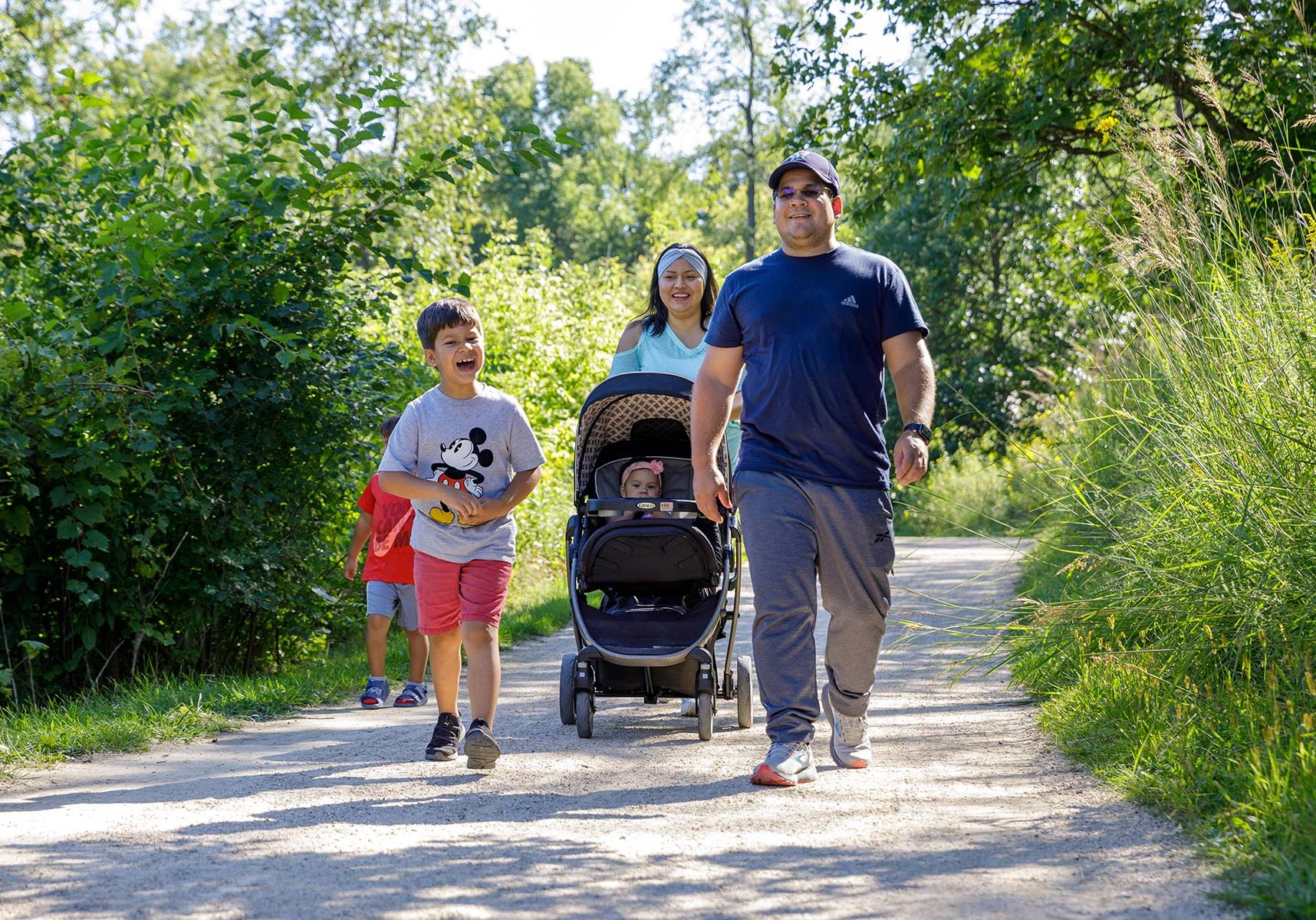 a man and two children walking down a path with a stroller